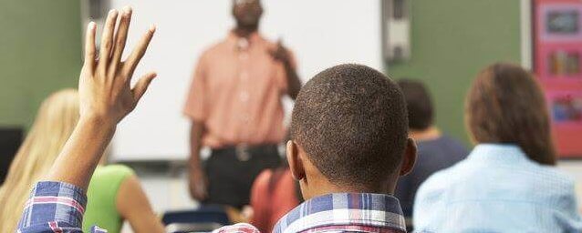 Student raising their hand in classroom | Guild Education